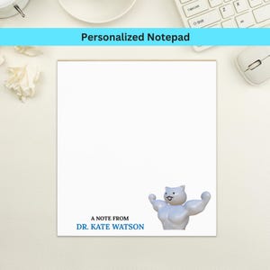 May include: White notepad with the text "Personalized Notepad" in a blue banner. The notepad features a cartoon cat flexing its muscles and the text "A note from Dr. Kate Watson" in blue.