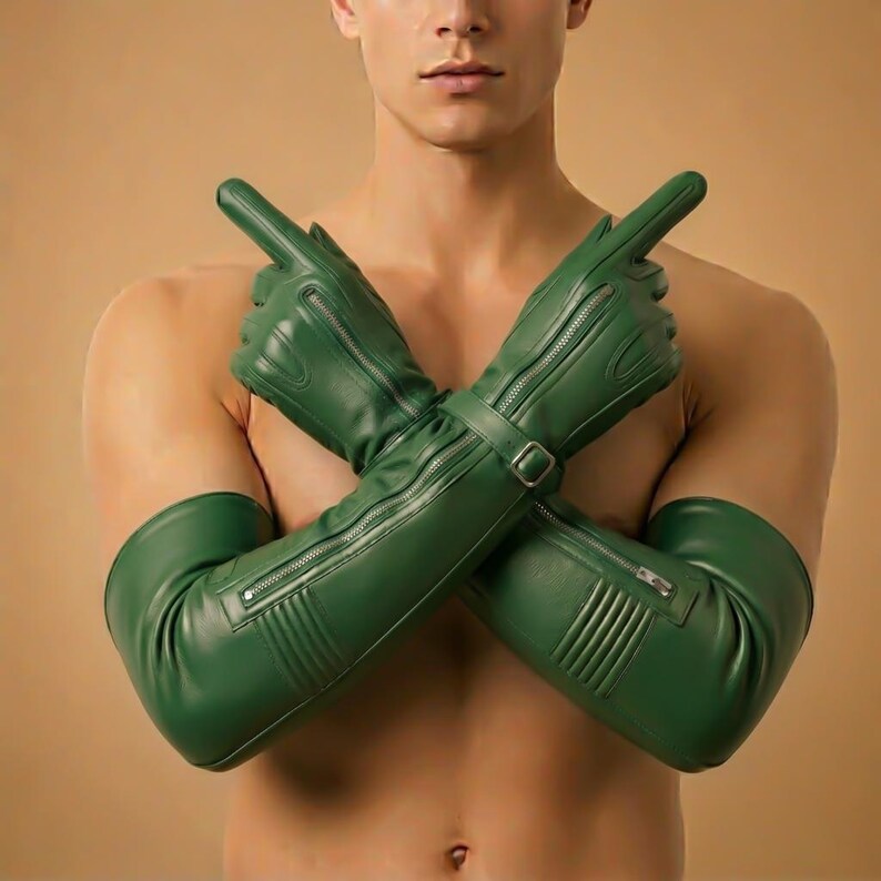 May include: Green leather gloves with long sleeves, featuring zippers and a buckle closure. The gloves are a vibrant green color and have a sleek, modern design. The gloves are shown with the arms crossed.
