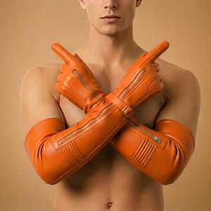 May include: Orange leather gloves with long sleeves, featuring zipper details and a buckle closure. The gloves are a vibrant shade of orange and appear to be made of a smooth leather material. The gloves are designed to cover the hands and extend up the arms.