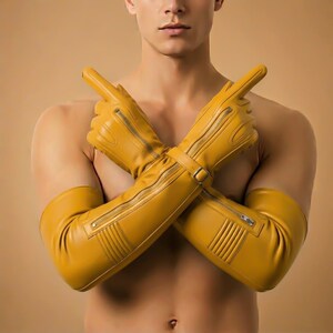 May include: Mustard yellow leather gloves with long sleeves. The gloves feature a zipper detail along the top and a buckle closure at the wrist. The gloves are made of a smooth, shiny leather material.