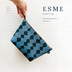 May include: A blue project bag with a diamond pattern and a brown handle. The bag has the text "ESME project bag" and "PDF sewing pattern / two sizes". The bag is held by a hand.