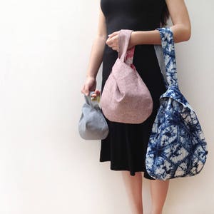 Puede incluir: Tres bolsas de tela de mano en diferentes colores y patrones. Las bolsas est&aacute;n hechas de una tela suave y natural y tienen un dise&ntilde;o simple y anudado. Las bolsas son de color azul claro, rosa claro y azul y blanco tie-dye.