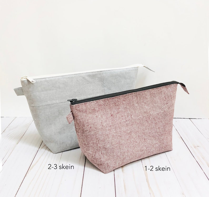 May include: Two fabric pouches in light gray and mauve. The gray pouch has a white zipper and the text "2-3 skein". The mauve pouch has a black zipper and the text "1-2 skein". Both pouches are rectangular with a trapezoidal shape.