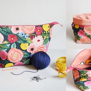 May include: Floral print fabric project bag with a zipper closure, a matching open-top basket, and a smaller open bag. The bags feature a dark background with pink, peach, yellow, and blue flowers. A ball of blue yarn and a yellow measuring tape are also present.