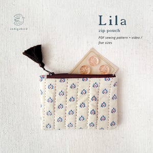 May include: A cream zip pouch with a floral pattern in blue and red. The pouch is open, revealing three decorative buttons and a brown zip. The text "Lila zip pouch" is visible, along with the logo "indigobird".