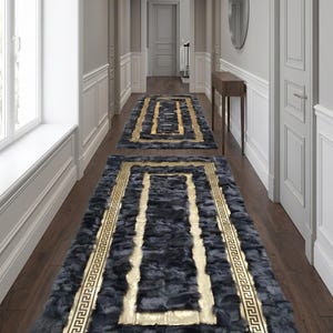 May include: Two dark gray hallway runners with gold geometric borders and accents. The rugs are placed on a dark wood floor in a hallway with white trim and doors. The runners have a plush, textured appearance.