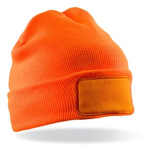 Puede incluir: Gorro de punto naranja brillante con un parche rectangular en la parte delantera. El gorro está hecho de una tela de punto acanalado y está diseñado para usarse en la cabeza. El parche es de un tono naranja más claro.