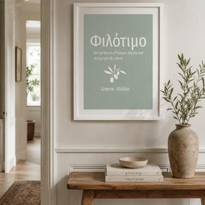 Puede incluir: Una lámina artística enmarcada con fondo verde salvia que presenta la palabra griega Φιλότιμο en texto blanco, seguida de la definición the Greek art of honour, dignity and doing right by others, un icono de rama de olivo y el texto Greece · Ελλάδα.