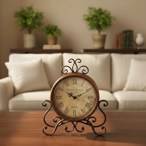 Puede incluir: Un reloj redondo de estilo vintage con números romanos y el texto "Winston Clock Co. Est. 1845". El reloj tiene un marco de metal color bronce y adornos decorativos. Está sobre una mesa de madera.