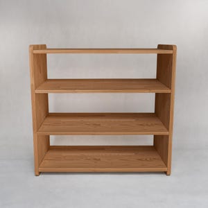 Può includere: Una libreria in legno marrone chiaro con tre ripiani. I ripiani sono supportati da due pannelli laterali. La libreria è realizzata in legno massello e ha una finitura naturale. Il design è semplice e funzionale.