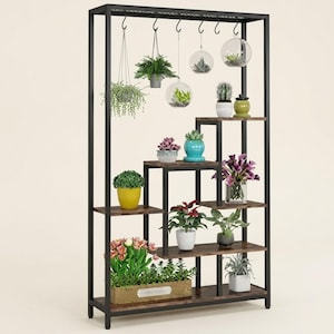 May include: A tall, rectangular black metal shelving unit with multiple staggered wooden shelves. The unit features hanging hooks at the top for glass globes and various potted plants, including succulents, flowers, and greenery in assorted pots.