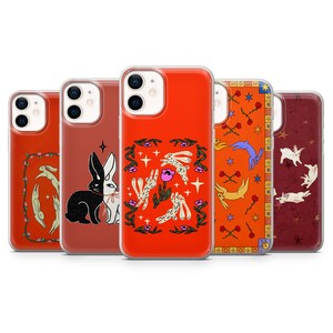 May include: Five phone cases with distinctive rabbit-themed designs. The cases showcase illustrations in shades of orange, red, and burgundy. The designs include floral patterns, stars, and a black and white rabbit. The cases are in a row.