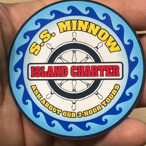 May include: A blue and yellow circular sticker with the text "S.S. MINNOW ISLAND CHARTER ASK ABOUT OUR 3-HOUR TOURS" and a black and white illustration of a ship's wheel.