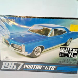 Puede incluir: Una taza de cerámica blanca con un asa negra y el texto "But First, Coffee" en negro, con una fuente de estilo manuscrito. La taza está sobre una superficie blanca.