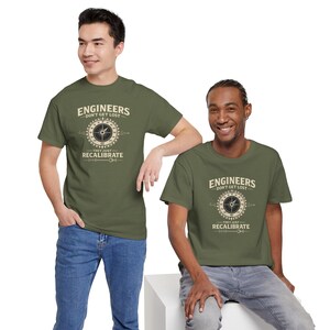 以下が含まれることがあります： 中央にコンパスのグラフィックが描かれたオリーブグリーンの半袖Tシャツ。コンパスの上には「ENGINEERS DON'T GET LOST」、下には「THEY JUST RECALIBRATE」という文字がクリーム色のヴィンテージ風フォントでプリントされています。