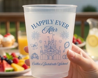 Könnte beinhalten: Ein gefrosteter Plastikbecher mit den Worten "Happily Ever After" und einem Schlossdesign in Blau. Der Becher enthält auch den Text "Caitlin's Bachelorette Weekend". Der Becher wird vor einer Gartenparty-Kulisse mit Essen und Getränken gehalten.