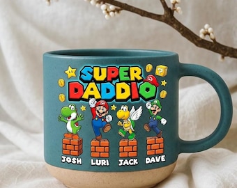 Könnte beinhalten: Türkisfarbene Keramik-Tasse mit beigefarbenem Boden, mit dem Text "SUPER DADDIO" und Cartoon-Figuren. Die Tasse hat einen Henkel und die Namen "JOSH", "LURI", "JACK" und "DAVE" darunter.