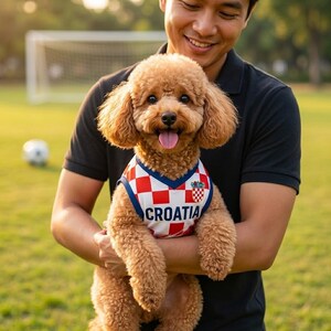May include: A small, light brown poodle wearing a sleeveless jersey featuring a red and white checkered pattern, a blue trim, and the word CROATIA printed in bold dark blue letters across the chest, with a small crest emblem on the upper left.