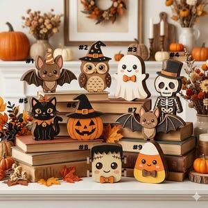 Pode incluir: Uma coleção de nove ornamentos de madeira com tema de Halloween, incluindo um morcego, coruja, fantasma, esqueleto, gato, abóbora, outro morcego, Frankenstein e um doce de milho, numerados de um a nove e dispostos sobre livros.