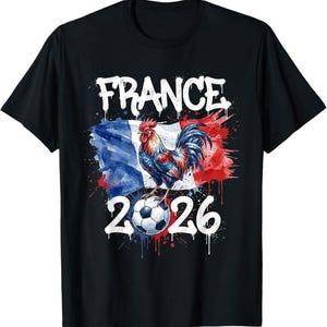 Op de afbeelding: Zwart T-shirt met een kleurrijke afbeelding van een haan op een voetbal voor een Franse vlag. Het woord "FRANCE" staat boven de vlag en het nummer "2026" eronder.