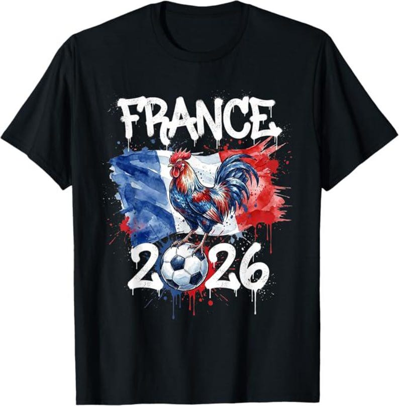 Op de afbeelding: Zwart T-shirt met een kleurrijke afbeelding van een haan op een voetbal voor een Franse vlag. Het woord "FRANCE" staat boven de vlag en het nummer "2026" eronder.