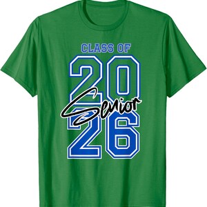 May include: Green t-shirt with the text "CLASS OF 2026 Senior" in blue and white lettering. The word "Senior" is in a cursive font. The shirt is a crew neck style.