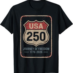 以下が含まれることがあります： 黒いTシャツ。USA 250とJourney of Freedom 1776-2026と書かれた、使い古された道路標識のデザイン。赤、ベージュ、黒の色使いで、ヴィンテージ感を醸し出しています。