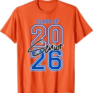 May include: Orange t-shirt with the text "CLASS OF 2026 Senior" in blue and white. The word "Senior" is in a cursive font. The shirt is a crew neck style.