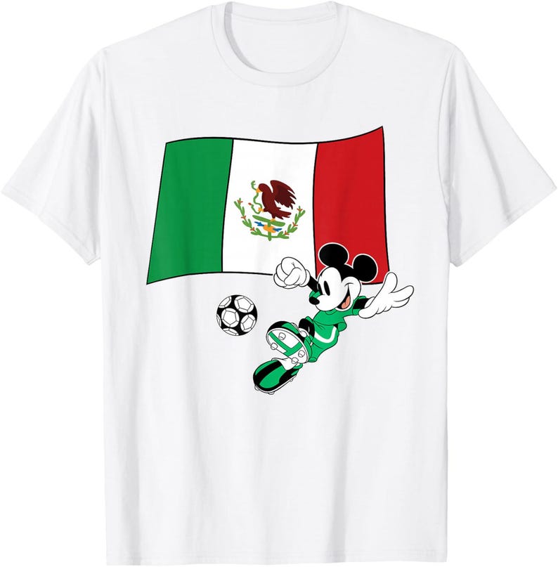 May include: White t-shirt featuring Mickey Mouse in a green soccer uniform kicking a soccer ball. Behind Mickey is the Mexican flag. The shirt is a classic crew neck style.