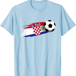 K&ouml;nnte beinhalten: Hellblaues T-Shirt mit einem kroatischen Flaggen-Design und einem Fu&szlig;ball. Die Flagge zeigt einen rot-wei&szlig; karierten Schild und eine Krone, mit einem rot-wei&szlig;-blauen Pinselstrich.