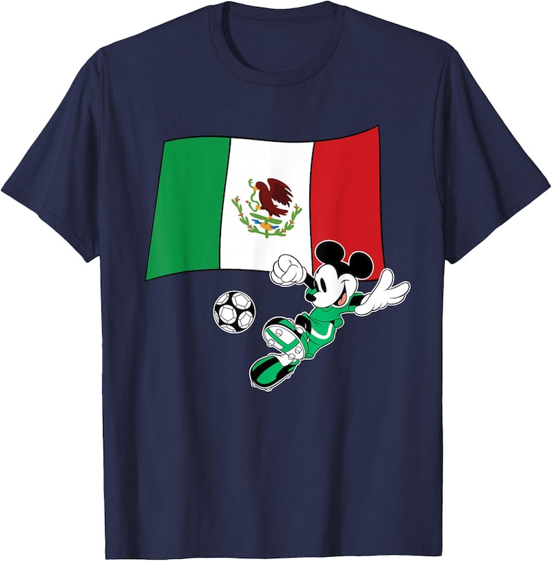 May include: Navy blue t-shirt featuring a graphic of Mickey Mouse in a green soccer uniform kicking a soccer ball. The Mexican flag is behind Mickey. The shirt is a crew neck.