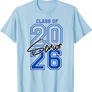 May include: Light blue t-shirt with the text "CLASS OF 2026 Senior" in blue and black. The numbers "2026" are in a bold, outlined font. The word "Senior" is in a cursive font, centered below the numbers.