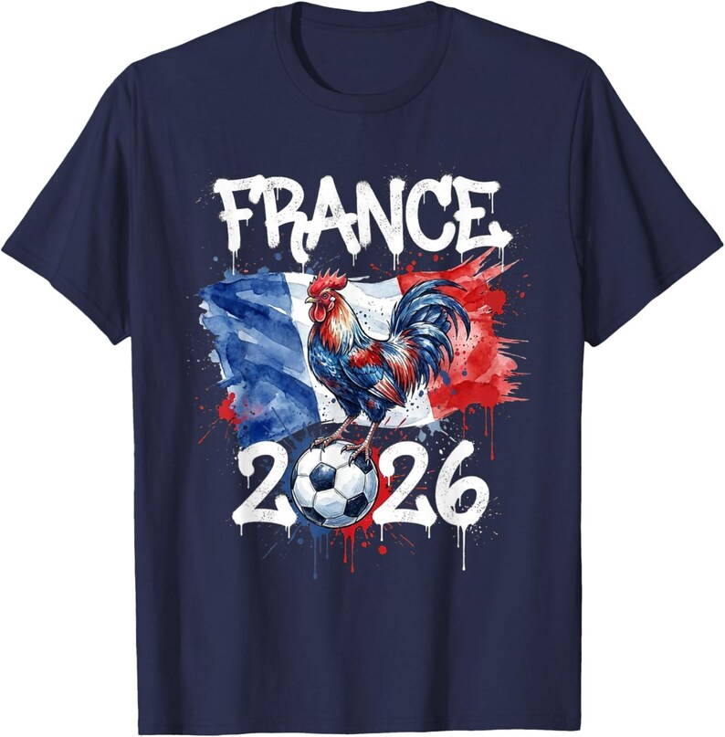 Op de afbeelding: Marineblauw T-shirt met een aquarelontwerp. Het toont het woord "FRANCE", een haan op een voetbal en het nummer "2026". Het ontwerp bevat de kleuren van de Franse vlag.