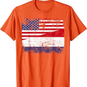 May include: Orange t-shirt featuring a distressed graphic combining the American and Dutch flags. The design shows the stars and stripes of the US flag alongside the red, white, and blue stripes of the Dutch flag. The shirt is a crew neck.