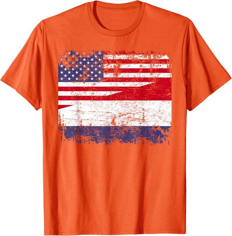 May include: Orange t-shirt featuring a distressed graphic combining the American and Dutch flags. The design shows the stars and stripes of the US flag alongside the red, white, and blue stripes of the Dutch flag. The shirt is a crew neck.