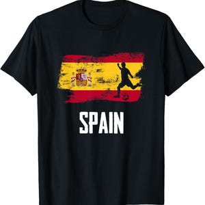 May include: A black short-sleeved t-shirt featuring a distressed graphic of the Spanish flag with a silhouette of a soccer player kicking a ball. The word SPAIN is printed in large white capital letters below the flag graphic on the chest.