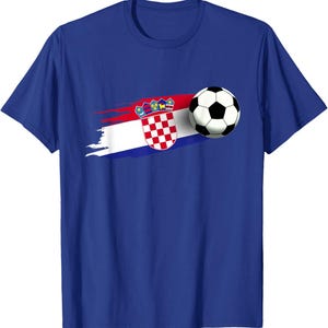 K&ouml;nnte beinhalten: Blaues T-Shirt mit einem Fu&szlig;ball und einer Grafik der kroatischen Flagge. Das Flaggen-Design umfasst einen rot-wei&szlig; karierten Schild, eine Krone und einen rot-wei&szlig;-blauen Pinselstrich.