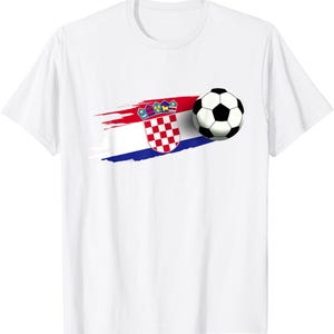 K&ouml;nnte beinhalten: Wei&szlig;es T-Shirt mit einer Grafik der kroatischen Flagge und einem Fu&szlig;ball. Das Flaggen-Design umfasst rote, wei&szlig;e und blaue Pinselstriche und ein kariertes Emblem. Der Fu&szlig;ball ist schwarz und wei&szlig;.
