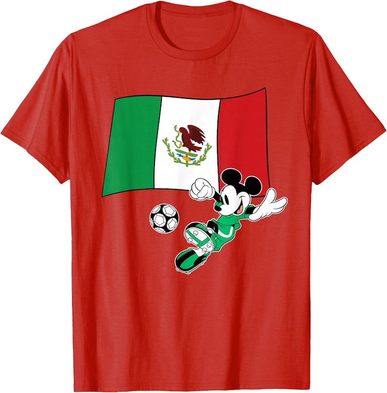 May include: Red t-shirt featuring a graphic of Mickey Mouse playing soccer in a green uniform. The Mexican flag is in the background, and a soccer ball is in front of Mickey. The shirt is made of a soft material.
