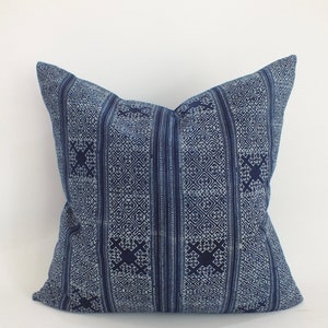 May include: A blue and white patterned throw pillow with a geometric design. The pillow is made of a soft, woven fabric.