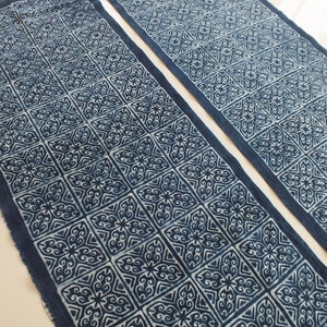 May include: Two indigo blue fabric table runners with a white geometric pattern. The pattern is a repeating square design with a floral motif.