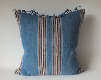 May include: Blue and white striped throw pillow with brown stripes. The pillow has a fringed edge.
