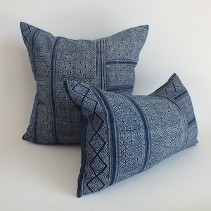 Puede incluir: Dos almohadas de tiro azules y blancas con un diseño geométrico.