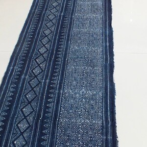 May include: A long piece of indigo blue fabric with a white geometric pattern. The fabric has a frayed edge and is folded in half.