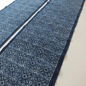 May include: Two pieces of indigo blue fabric with a white geometric pattern. The fabric has a raw edge and is folded in half.