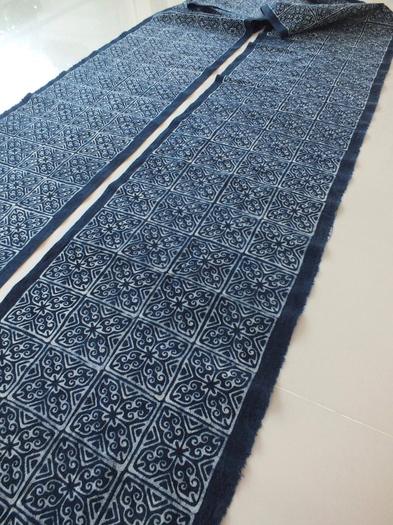 May include: Two pieces of indigo blue fabric with a white geometric pattern. The fabric has a raw edge and is folded in half.