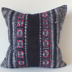May include: A black and white striped pillow with pink geometric designs. The pillow is made of a soft, woven fabric.