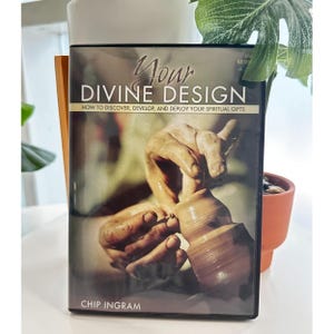 Op de afbeelding: Een dvd-hoes met de titel "Your Divine Design" en de ondertitel "How to Discover, Develop, and Deploy Your Spiritual Gifts". De cover toont handen die klei vormen op een pottenbakkerswiel. De naam van de auteur, Chip Ingram, staat onderaan.