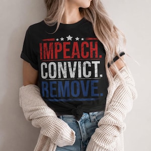 Puede incluir: Una camiseta negra de manga corta con un estampado gráfico desgastado con el texto IMPEACH en rojo, CONVICT en blanco y REMOVE en azul, dispuesto en tres líneas horizontales con cinco estrellas blancas sobre el texto.