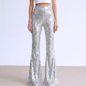 May include: Silver sequin flared pants. The high-waisted pants feature a wide leg design, covered in shimmering silver sequins. The pants are a statement piece, perfect for a party or special event.